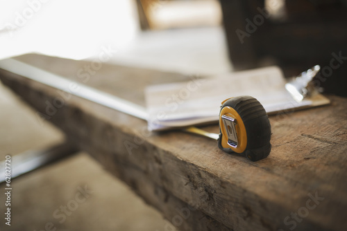 Foto: A reclaimed timber yard. Recycled plank of wood, measuring tape and a clipboard with paperwork. A reclaimed timber yard. Recycled plank of wood, measuring tape and a clipboard with paperwork.