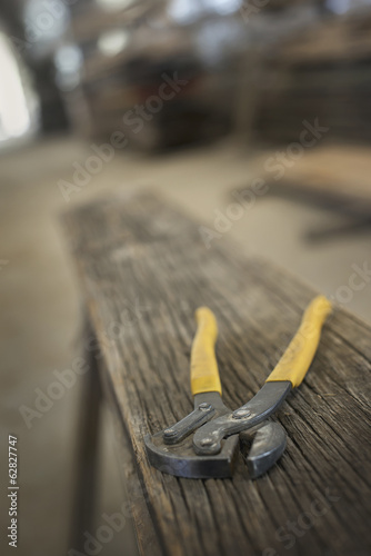Foto: A heap of recycled reclaimed timber planks of wood. Environmentally responsible reclamation in a timber yard. A pair of pliers on a plank of wood. A heap of recycled reclaimed timber planks of wood. Environmentally responsible reclamation in a timber yard. A pair of pliers on a plank of wood.