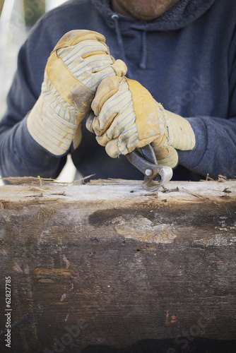 Foto: A reclaimed lumber workshop. A man preparing the timber by removing all the nails and studs. A reclaimed lumber workshop. A man preparing the timber by removing all the nails and studs.