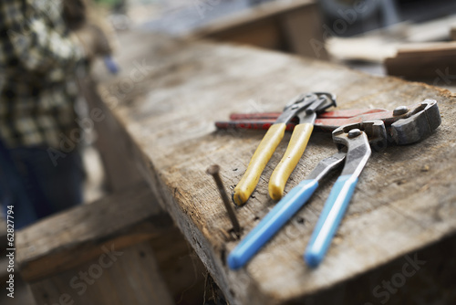 Foto: A reclaimed lumber workshop. A person at a workbench, and tools, grippers and pliers lined up on a plank of wood. A reclaimed lumber workshop. A person at a workbench, and tools, grippers and pliers lined up on a plank of wood.