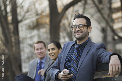 Foto: Business people in the city. Three people, two men and a woman in a city park relaxing. Business people in the city. Three people, two men and a woman in a city park relaxing.