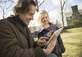 Photo: An Organic Farm in Winter in Cold Spring, New York State. A man holding a digital tablet in his hands, showing his child the screen. An Organic Farm in Winter in Cold Spring, New York State. A man holding a digital tablet in his hands, showing his child the screen.