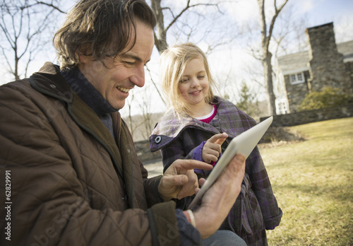 Photo: An Organic Farm in Winter in Cold Spring, New York State. A man holding a digital tablet in his hands, showing his child the screen. An Organic Farm in Winter in Cold Spring, New York State. A man holding a digital tablet in his hands, showing his child the screen.