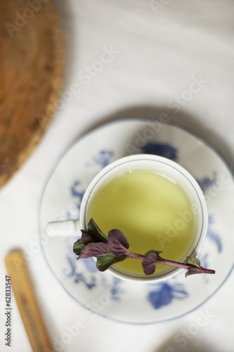 Photo: A cup of tea, clear coloured tea in a china cup, with a sprig of aromatic mint. A cup of tea, clear coloured tea in a china cup, with a sprig of aromatic mint.