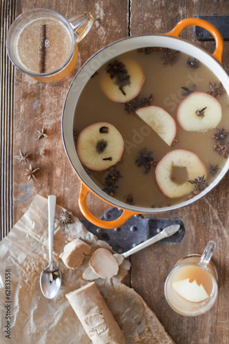 Photo: Overhead view of a kitchen table. A large cooking pan with double handles. Sliced cored apples, cloves and star anise with cinnamon. Making a mulled fruit drink. Overhead view of a kitchen table. A large cooking pan with double handles. Sliced cored apples, cloves and star anise with cinnamon. Making a mulled fruit drink.