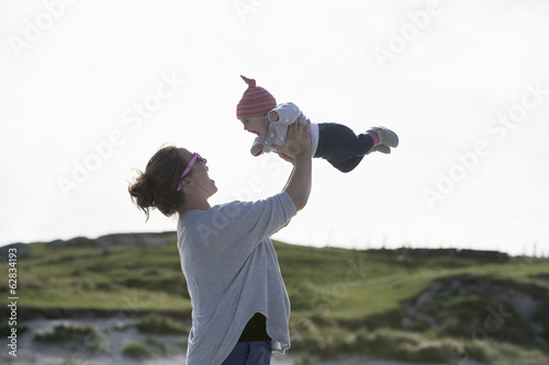 Photo: A mother raising her baby in the air. At the seaside. A mother raising her baby in the air. At the seaside.