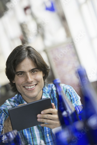 Photo: A cafe interior. A man sitting using a digital tablet. A cafe interior. A man sitting using a digital tablet.