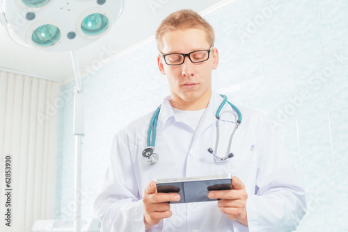 Photo: Physician works on a tablet computer in a clinic Physician works on a tablet computer in a clinic