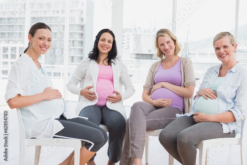 Photo: Smiling pregnant women sitting together at antenatal class Smiling pregnant women sitting together at antenatal class