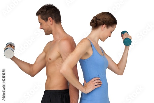 Photo: Fit young couple exercising with dumbbells Fit young couple exercising with dumbbells