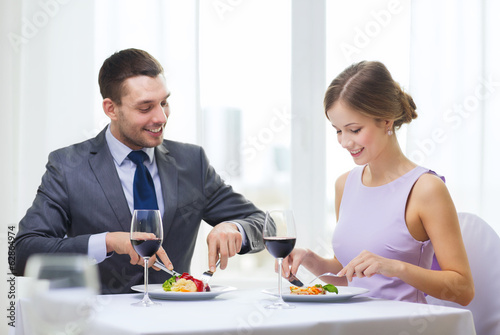 Photo: smiling couple eating main course at restaurant smiling couple eating main course at restaurant