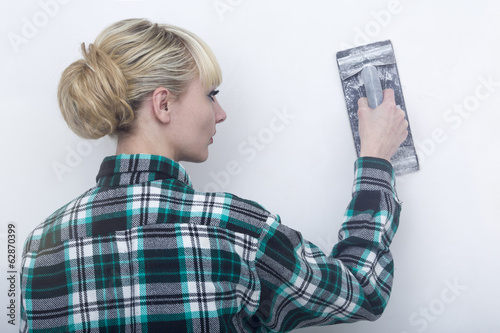 Photo: Woman, smooths out hard putty on a wall an emery paper Woman, smooths out hard putty on a wall an emery paper