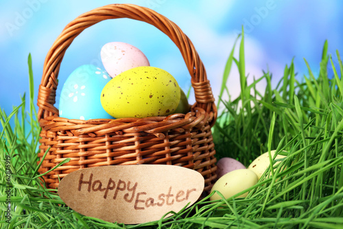Photo: Easter composition with eggs on green grass, on blue background Easter composition with eggs on green grass, on blue background