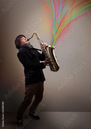 Photo: Attractive musician playing on saxophone while colorful abstract Attractive musician playing on saxophone while colorful abstract