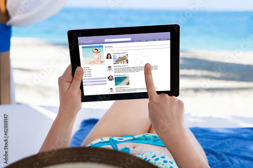Photo: Woman Surfing On Social Site At Beach Woman Surfing On Social Site At Beach