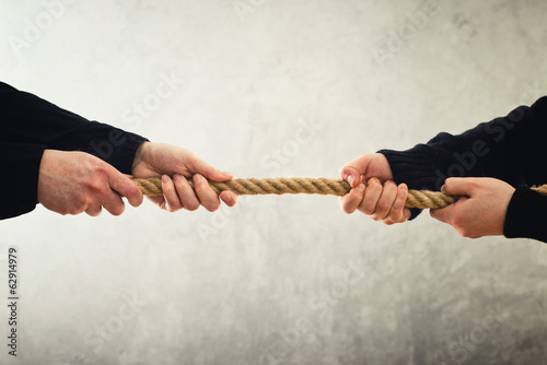 Photo: Tug of war. Hands pulling rope to opposite sides Tug of war. Hands pulling rope to opposite sides