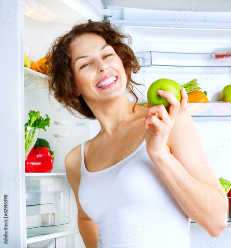 Photo: Diet. Beautiful young woman near the fridge with healthy Food Diet. Beautiful young woman near the fridge with healthy Food