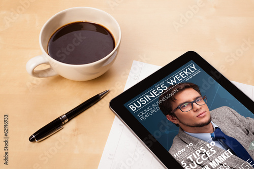 Photo: Tablet pc showing magazine on screen with a cup of coffee on a d Tablet pc showing magazine on screen with a cup of coffee on a d