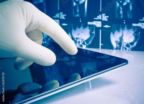 Photo: hand in glove touching modern digital tablet on x-ray images hand in glove touching modern digital tablet on x-ray images