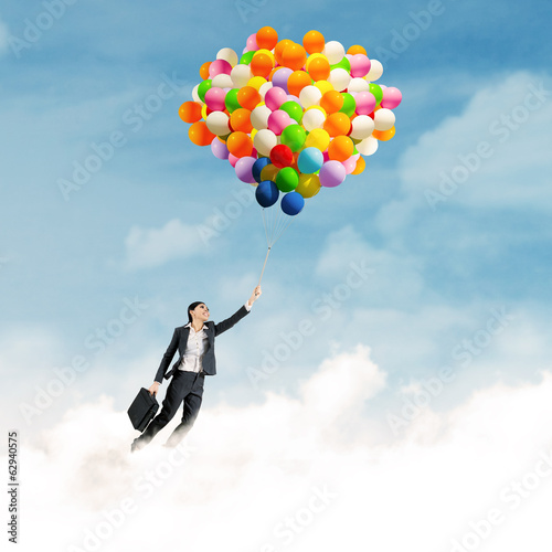 Photo: Businesswoman flying with balloons Businesswoman flying with balloons