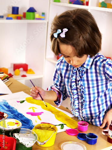 Photo: Child painting at easel. Child painting at easel.