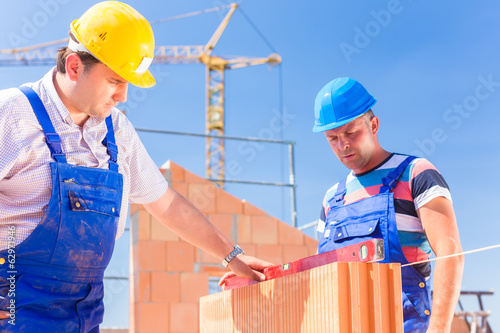Photo: Zwei Handwerker kontrollieren Wände auf Baustelle Zwei Handwerker kontrollieren Wände auf Baustelle
