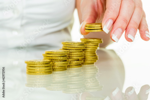 Photo: Frau mit Münzstapel beim Geld sparen Frau mit Münzstapel beim Geld sparen