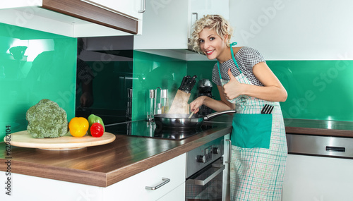 Photo: Young woman cook or housewife gesturing thumbs up Young woman cook or housewife gesturing thumbs up