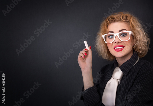Photo: Cute teacher with chalk in front of blackboard Cute teacher with chalk in front of blackboard