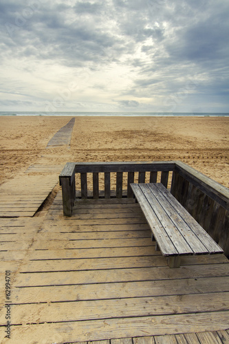Photo: View of wooden passage in a long empty beach shoreline. View of wooden passage in a long empty beach shoreline.