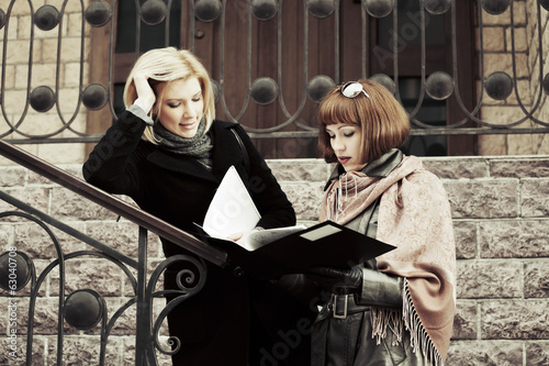 Photo: Two young business women with financial folder Two young business women with financial folder