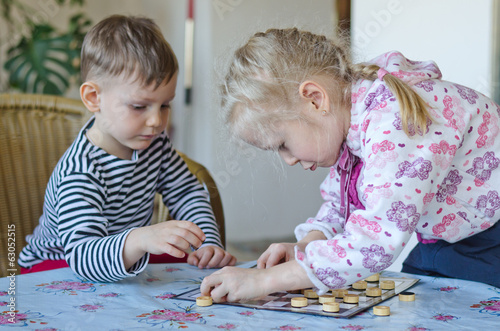 Photo: Young girl and boy playing checkers together Young girl and boy playing checkers together
