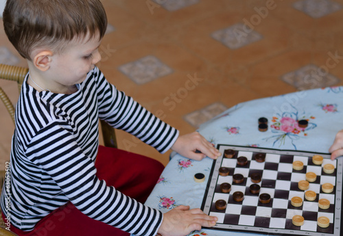 Photo: Little boy setting up a game of checkers Little boy setting up a game of checkers