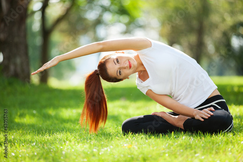 Photo: Pretty woman doing yoga exercises in the park Pretty woman doing yoga exercises in the park