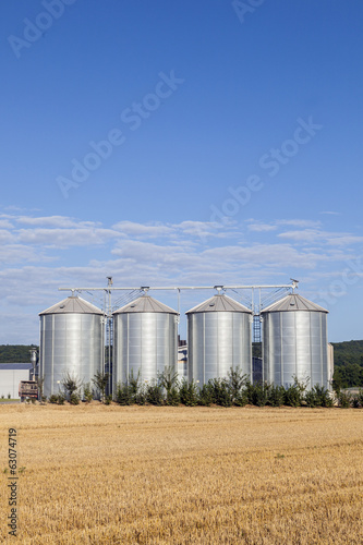Photo: four silver silos in the field after the harvest four silver silos in the field after the harvest