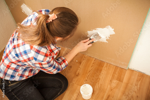 Photo: Brunette woman plastering wall at house Brunette woman plastering wall at house