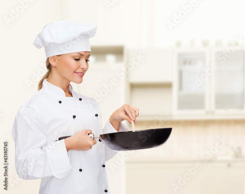 Photo: smiling female chef with pan and spoon smiling female chef with pan and spoon