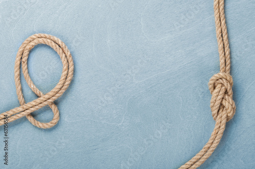 Photo: Ship rope knot on wooden texture background Ship rope knot on wooden texture background