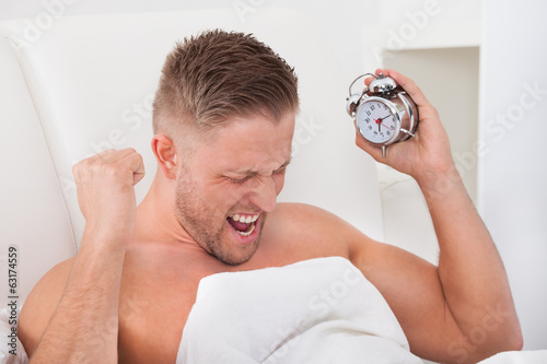 Photo: Man screaming in frustration at his alarm clock Man screaming in frustration at his alarm clock