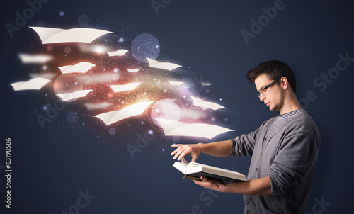 Photo: Young guy reading a book with flying sheets coming out of the bo Young guy reading a book with flying sheets coming out of the bo