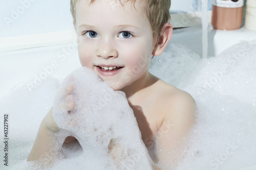 Photo: Smiling Little Boy in the Bath.Funny Child in Foam. Blue Eyes Smiling Little Boy in the Bath.Funny Child in Foam. Blue Eyes