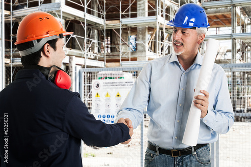 Photo: Workers shaking hands in a construction site Workers shaking hands in a construction site
