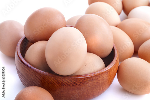 Photo: Healthy domestic eggs in a wooden bowl on a white background Healthy domestic eggs in a wooden bowl on a white background