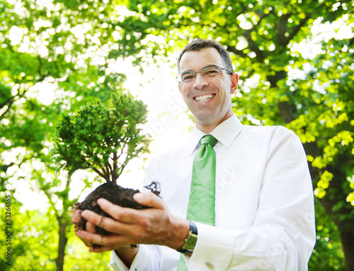 Photo: Businessman Holding A Tree To Plant In A Forest Businessman Holding A Tree To Plant In A Forest