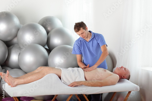 Photo: therapist massaging middle age man' s abdomen therapist massaging middle age man' s abdomen