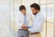 Businessmen looking at digital tablet in office Businessmen looking at digital tablet in office