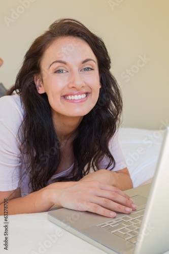Photo: Relaxed woman using laptop in bed at home Relaxed woman using laptop in bed at home