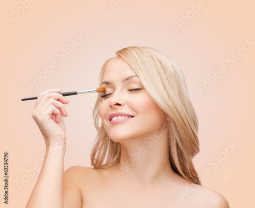 Photo: beautiful woman with closed eyes and makeup brush beautiful woman with closed eyes and makeup brush