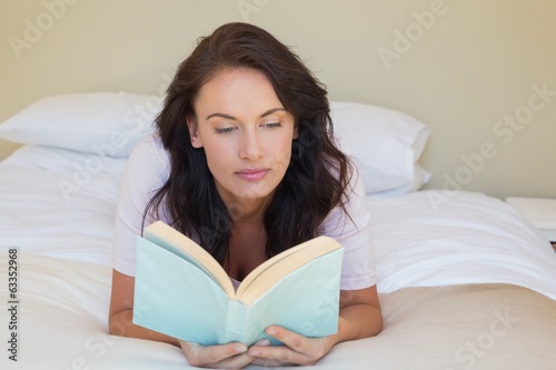 Photo: Woman reading book while lying in bed Woman reading book while lying in bed