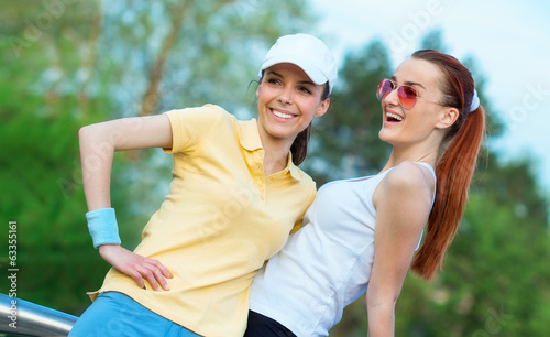 Photo: Friendship of smiling girl friends in sports clothing Friendship of smiling girl friends in sports clothing